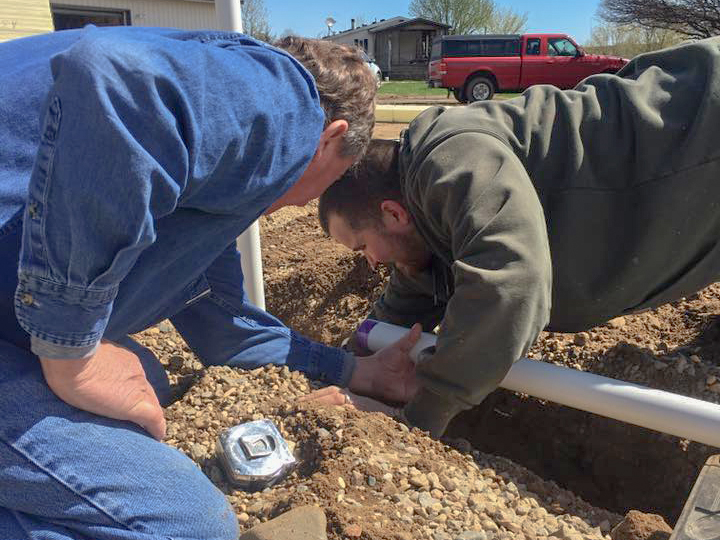 action-shot3_h two Reich's Plumbing and Heating employees digging in ground to add a pipe